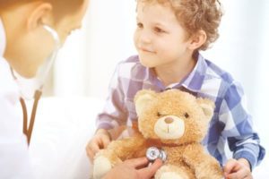 Young child holding teddy bear with doctor