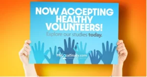 person holding a sign that says "Now Accepting Healthy Volunteers"